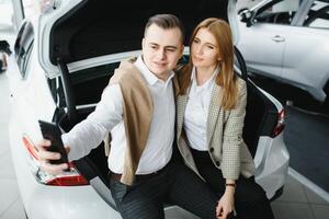 familia selfie en concesión. contento joven Pareja elige y comprando un nuevo coche para el familia foto