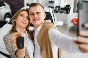 familia selfie en concesión. contento joven Pareja elige y comprando un nuevo coche para el familia foto