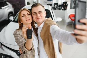 familia selfie en concesión. contento joven Pareja elige y comprando un nuevo coche para el familia foto