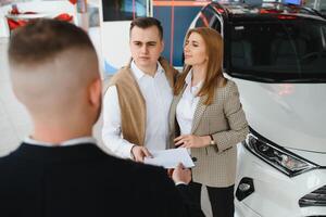 mature salesman showing new car to a couple in showroom. photo