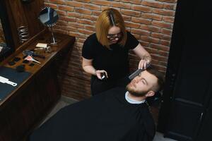 Client during beard shaving in barber shop photo