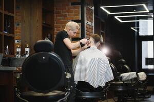 Young handsome barber making haircut of attractive bearded man in barbershop. photo