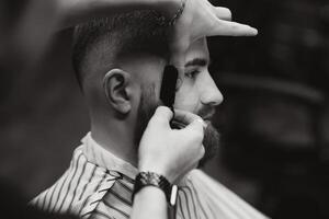 Close up image of barber shaving a man with a sharp steel razor photo