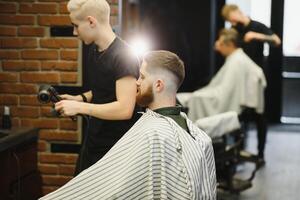 Barber shop. Man in barber's chair, hairdresser styling his hair. photo