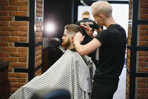 Barber shop. Man in barber's chair, hairdresser styling his hair. photo