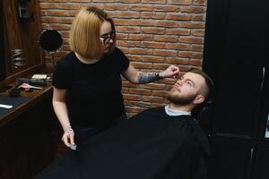 Client during beard shaving in barber shop photo