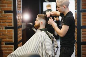 Barber shop. Man in barber's chair, hairdresser styling his hair. photo