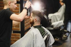 Barber shop. Man in barber's chair, hairdresser styling his hair. photo