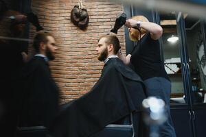 Serving client in Barbershop. Professional barber girl, female hairdresser making modern haircut for a man sitting in barber shop chair. Focus on a girl. Hairdressing, shaving, trimming, grooming. photo