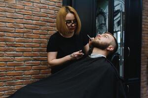 Client during beard shaving in barber shop photo