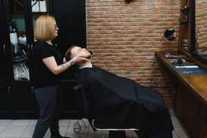 Client during beard shaving in barber shop photo