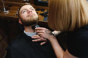 Client during beard shaving in barber shop photo