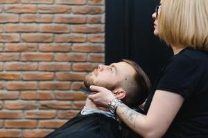 Client during beard shaving in barber shop photo