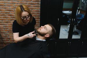 Client during beard shaving in barber shop photo