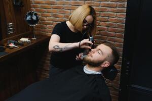 Client during beard shaving in barber shop photo