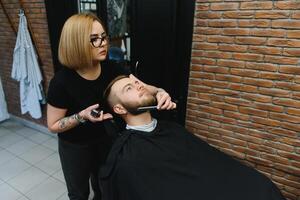 Client during beard shaving in barber shop photo