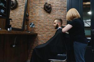 Barber Woman Cutting Man Hair at the Barbershop. Woman Working as a Hairdresser. Small Business Concept. photo