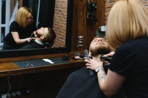 Client during beard shaving in barber shop photo