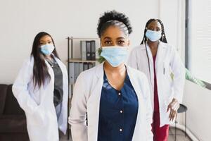 Group of African American female doctors in protective masks on their faces. photo