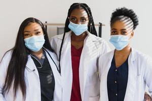 Group of healthcare workers wearing protective face masks while standing with arms crossed and looking at camera photo