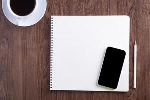 Top view of a smartphone, sketchbook, a pencil, a white coffee cup placed on a wooden table. Template for text. Wood texture background. Concept of drawing and technology photo