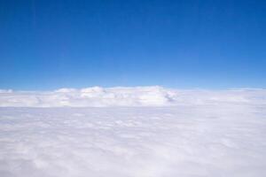 Aerial view of sky seen through the airplane window. Bright blue sky and white clouds with skyline background. Space for text photo