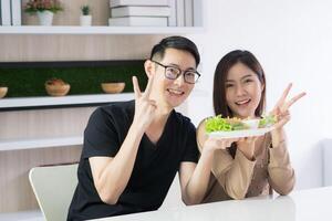 Young couple holding a dish of fresh vegetables smiling and looking at the camera. Diet foods, low calories. Eat vegetables organic for good health. Healthy foods concept photo