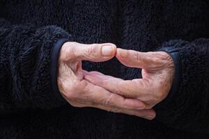 Close-up of wrinkled hands senior woman joined together for meditation. Concept of aged people and religion photo