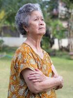 Portrait of a senior woman with arms raised and looking up while standing in a garden. Concept of aged people and healthcare photo