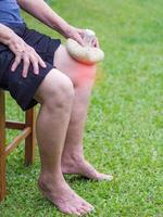 mayor mujer teniendo utilizar un tailandés herbario comprimir pelota en el rodilla. rodilla dolor mayo porque por músculo tendinosis, osteoartritis. foto