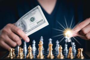 Front view of a chess game with blur background. Close-up of a young man hand holding dollar currency playing chess. Business game competitive strategy. Concept of strategy for business photo