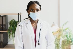 medicine, profession and healthcare concept - african american female doctor or scientist in protective facial mask in clinic. photo