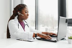 Telehealth, African American doctor in headset consulting with the patient over the phone call. Health care call center and telehealth online concept. photo