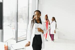 health care, profession, people and medicine concept - happy african american female doctor or nurse over group of medics meeting at hospital. photo