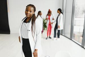 salud cuidado, profesión, personas y medicina concepto - contento africano americano hembra médico o enfermero terminado grupo de medicos reunión a hospital. foto