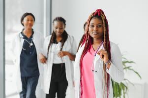 salud cuidado, profesión, personas y medicina concepto - contento africano americano hembra médico o enfermero terminado grupo de medicos reunión a hospital. foto