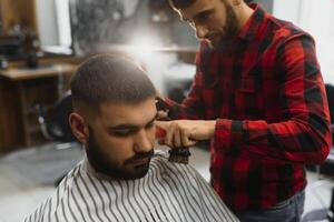 Barber shop. Man with wife in barber's chair, hairdresser Barbershop styling his hair. photo