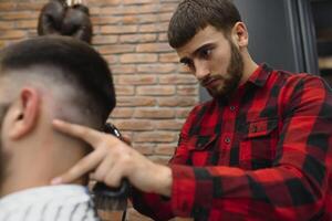 Serious Young Bearded Man Getting Haircut By Barber. Barbershop Theme. photo