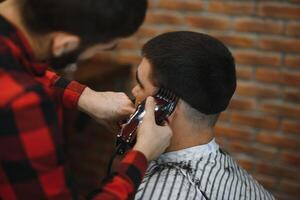 Barber shop. Man with wife in barber's chair, hairdresser Barbershop styling his hair. photo