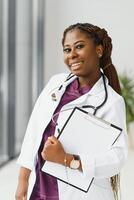 Portrait of female African American doctor standing in her office at clinic. photo