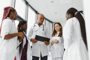 Afro-American doctor leading his team with folded arms and looking at the camera. photo