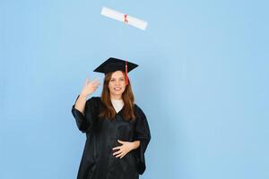 Beautiful woman wearing graduation cap and ceremony robe holding degree looking positive and happy standing and smiling with a confident smile. photo