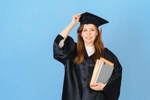 Beautiful woman wearing graduation cap and ceremony robe holding degree looking positive and happy standing and smiling with a confident smile. photo