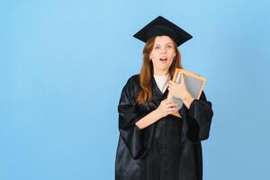 Woman graduate student wearing graduation hat and gown, on blue background photo