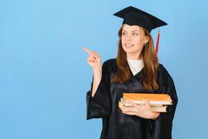 Woman graduate student wearing graduation hat and gown, on blue background photo