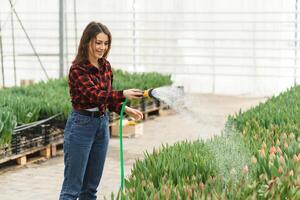 happy florist watering flowers in greenhouse. photo