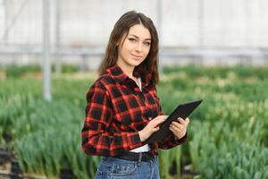 Beautiful young smiling girl, worker with flowers in greenhouse. Concept work in the greenhouse, flowers. photo