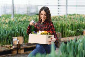 Beautiful young smiling Florists woman, worker with flowers in greenhouse. Concept work in the greenhouse, flowers. photo