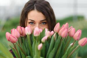 Beautiful young smiling girl with tablet, worker with flowers in greenhouse. Concept work in the greenhouse, flowers. photo