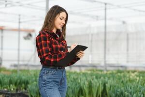 Beautiful young smiling girl, worker with flowers in greenhouse. Concept work in the greenhouse, flowers. photo